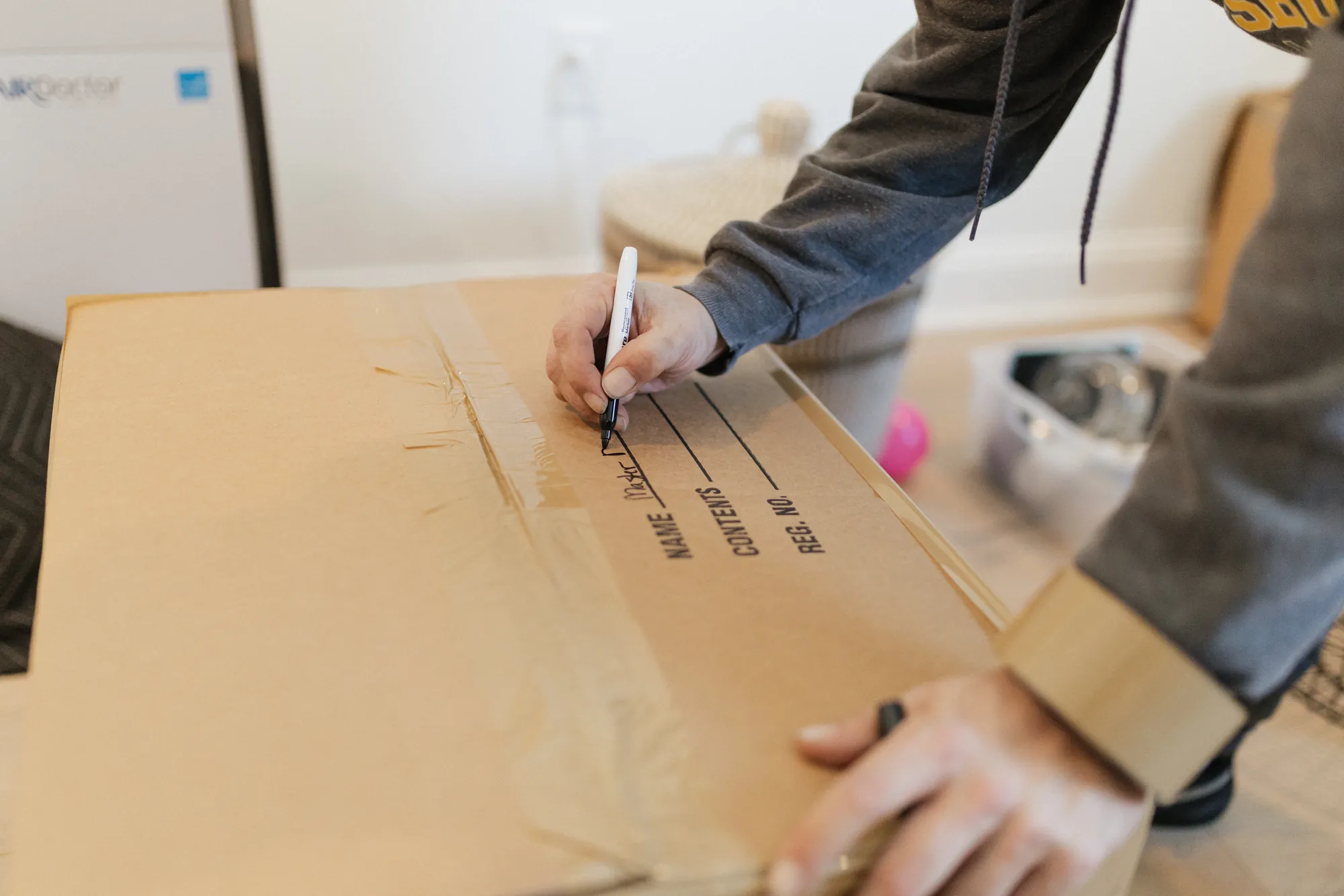 Mover labeling a sealed moving box with its contents during packing.