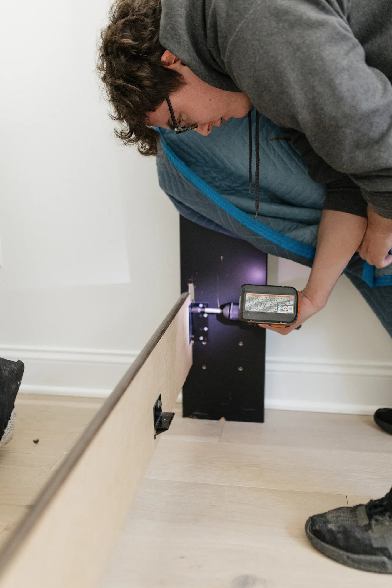 Two movers reassembling furniture with a cordless drill after a move.