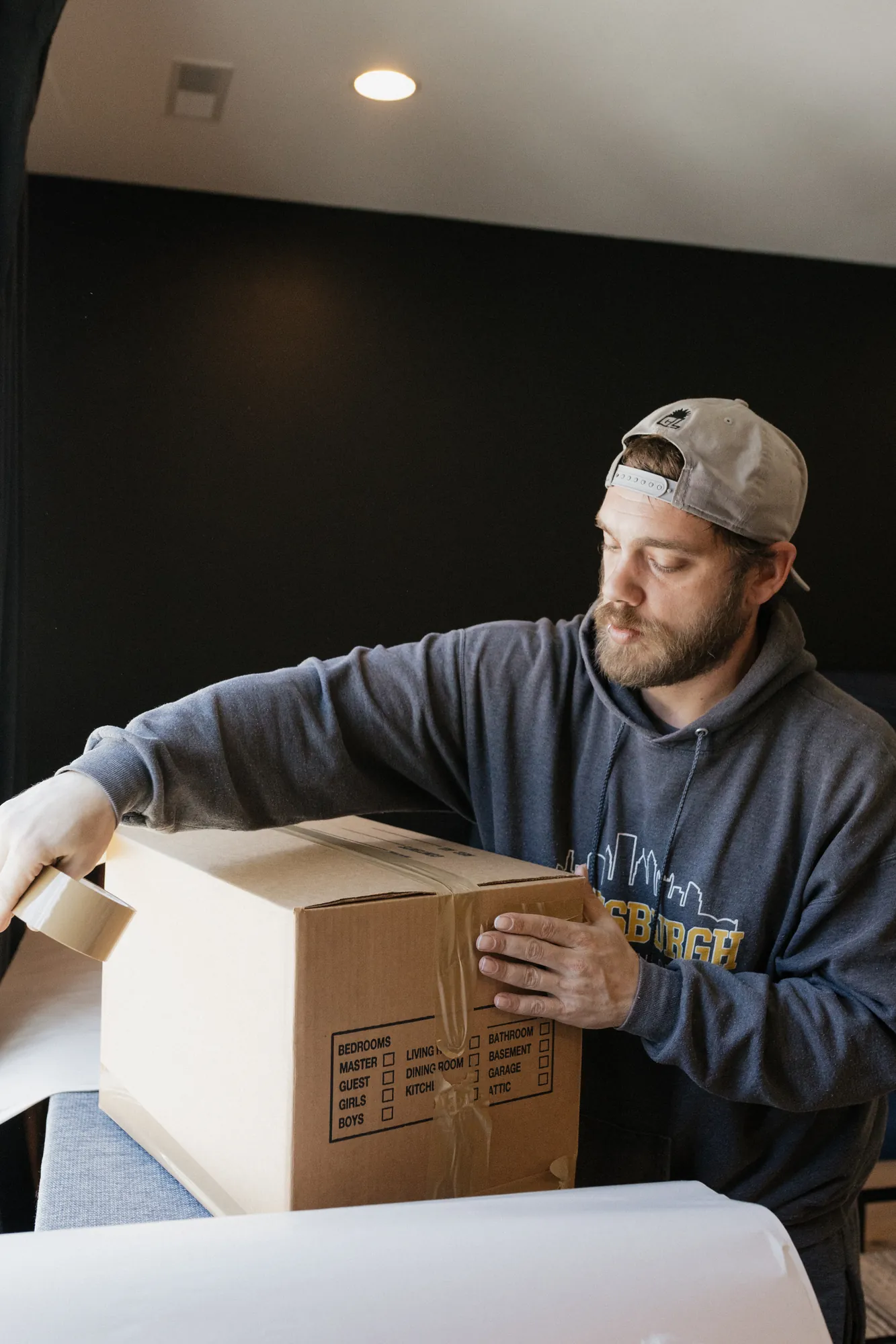 Pittsburgh Moving PGH crew member sealing a labeled moving box with packing tape.
