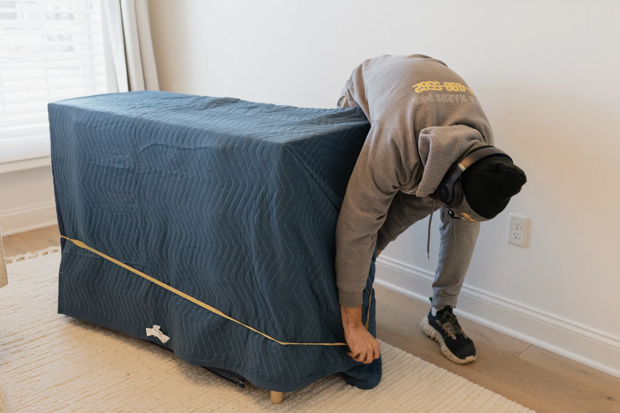 Pittsburgh Moving PGH mover strapping a blanket-wrapped piece of furniture inside a home.