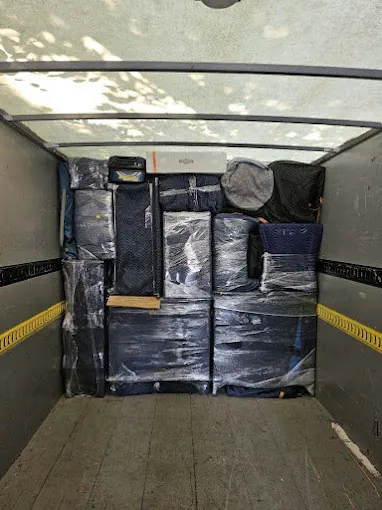 Blanket-wrapped furniture strapped and loaded inside a moving truck.